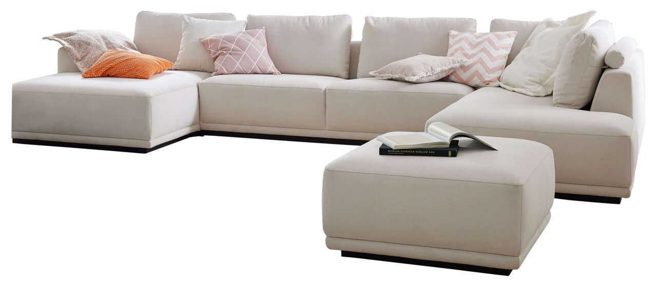 Beige Polsterrundecke mit mehreren Kissen in verschiedenen Farben und Mustern, aus einer leicht erhöhten Perspektive fotografiert.