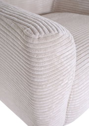 Detailfoto van de armleuning van een lichtbeige corduroybank met een zachte, geribbelde structuur, schuin van voren bovenaf gefotografeerd
