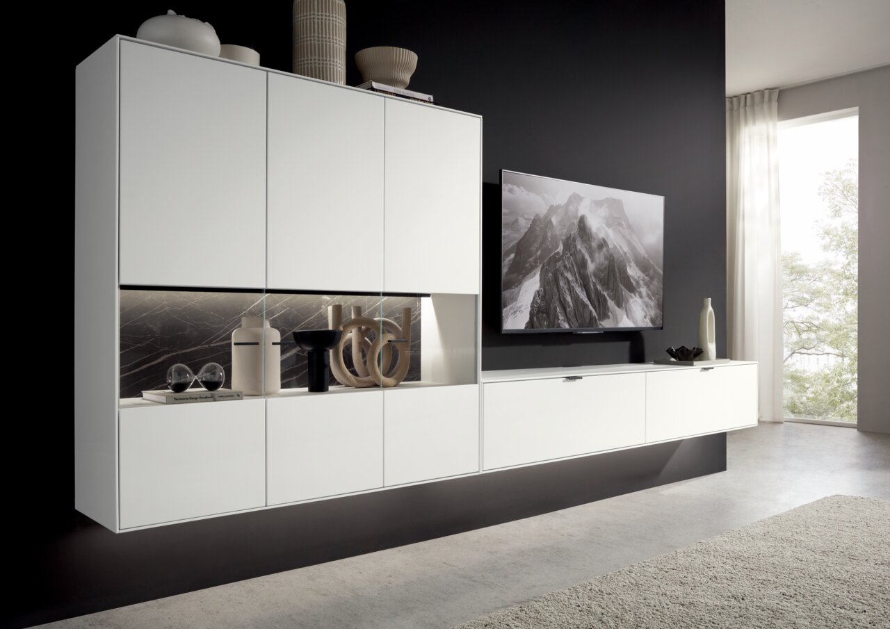 Moderne weiße Wandkombination mit dekorativen Elementen und einem Fernseher, seitliche Perspektive