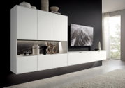 Moderne weiße Wandkombination mit dekorativen Elementen und einem Fernseher, seitliche Perspektive