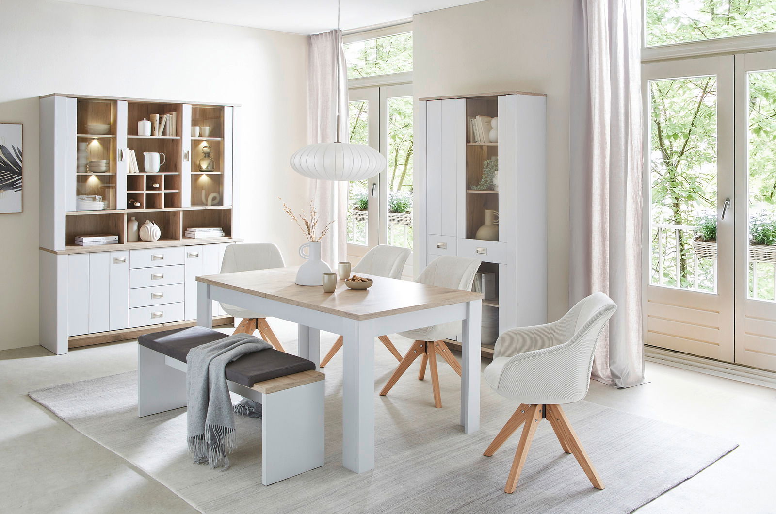 Hom´in Sideboard ETIENNE Esszimmer mit modernem Esstisch, Stühlen und Bank in heller, freundlicher Atmosphäre. Perspektive von vorne auf den Tisch und die umgebenden Möbel.