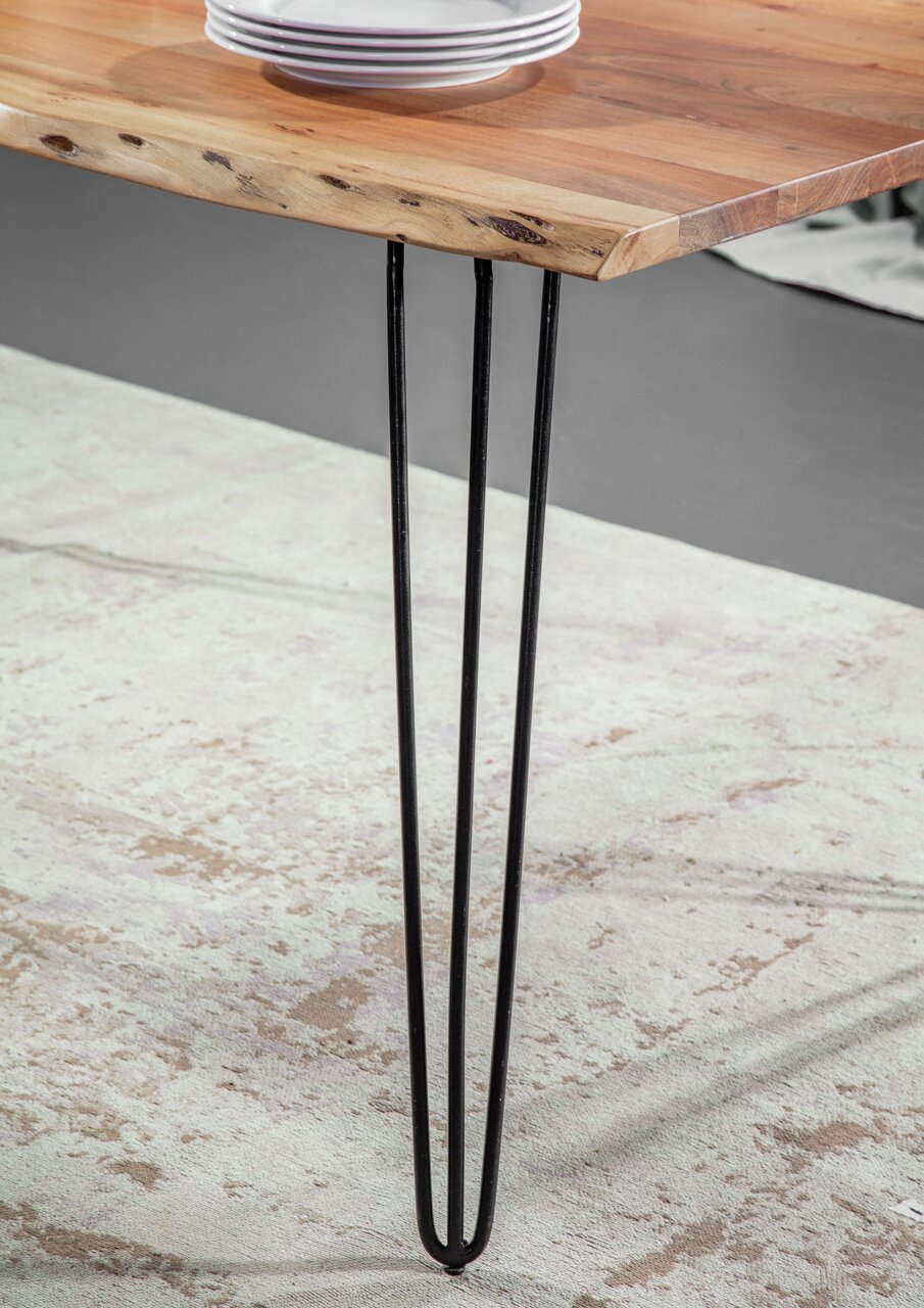 Nahaufnahme eines Esstisches mit einer Tischplatte aus Holz und schwarzen Metallbeinen, seitliche Perspektive.