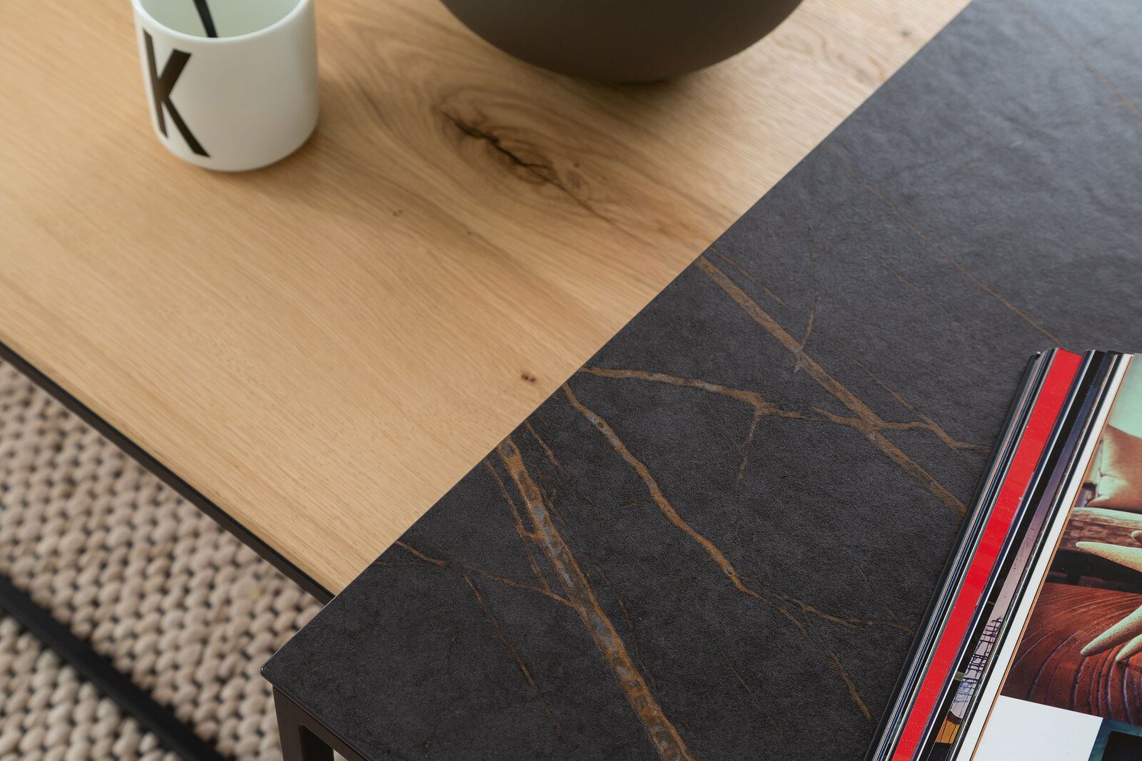 Nahaufnahme eines modernen Beistelltisches mit einer Kombination aus heller Holz- und dunkler Steinoptik, von oben fotografiert.