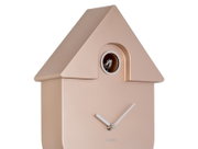 Moderne wandklok in de vorm van een minimalistisch koekoeksklokhuisje, gezien vanaf de zijkant, met een klein vogeltje bovenaan en eenvoudige witte wijzers op een gouden wijzerplaat.