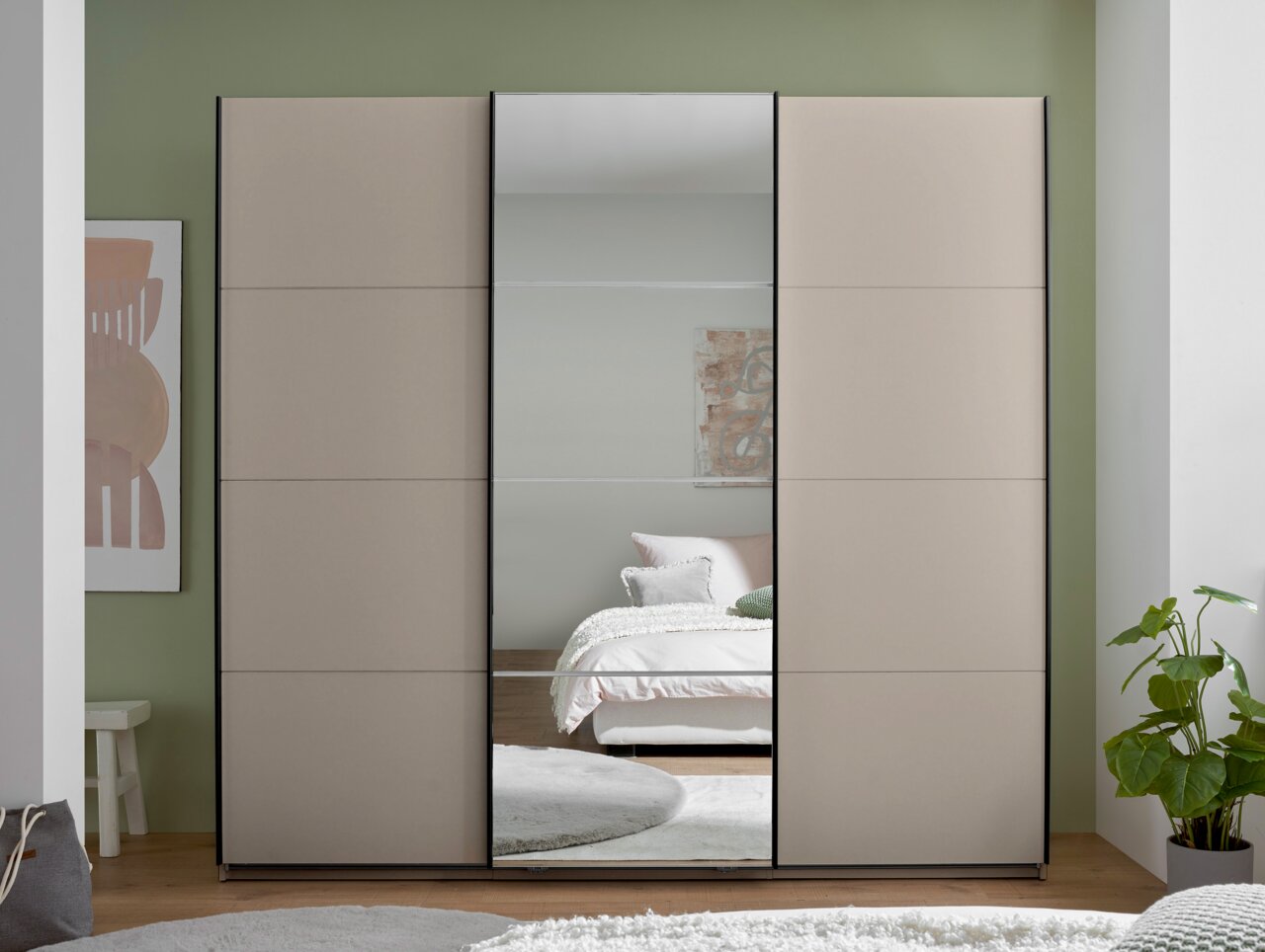 Moderner Schwebetürenschrank in Beige mit mittiger Spiegeltür und schwarzen Rahmenkanten, frontal aus Augenhöhe im Schlafzimmer fotografiert.