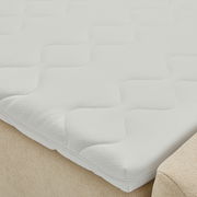 Nahaufnahme eines Boxbetts mit weißem, strukturiertem Matratzenbezug in seitlicher Perspektive.