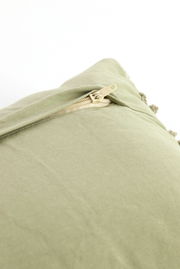 Nahaufnahme eines grünen Kissens mit Reißverschluss, perspektivisch von oben fotografiert.