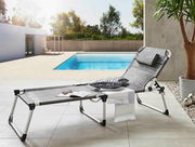 Moderne Liege am Pool mit Kissen und Handtuch, seitliche Perspektive
