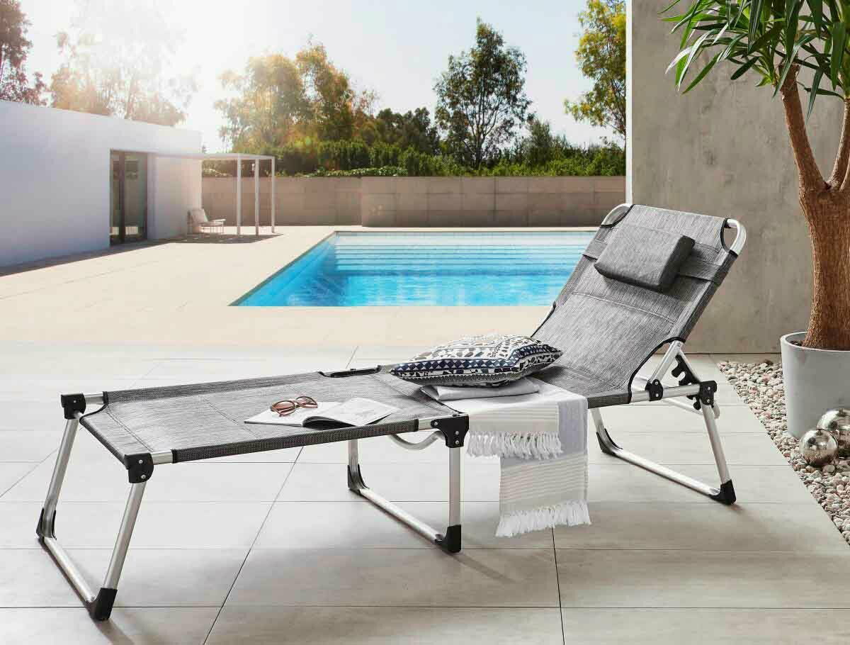 Moderne Liege am Pool mit Kissen und Handtuch, seitliche Perspektive