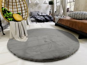 Runder grauer Fellteppich in einem modernen Schlafzimmer mit Hängesessel und braunem Bett, aus der Vogelperspektive betrachtet.