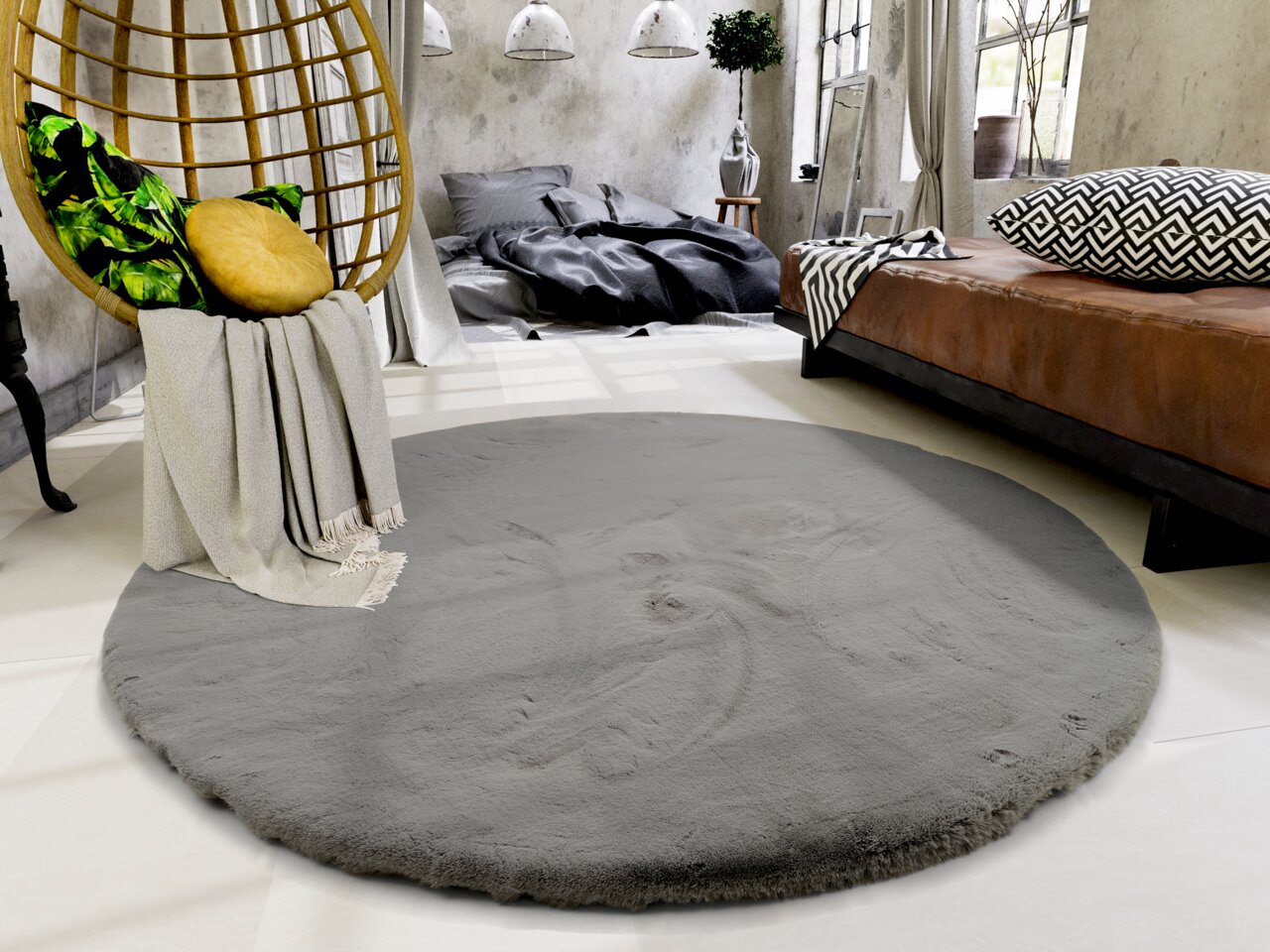 Runder grauer Fellteppich in einem modernen Schlafzimmer mit Hängesessel und braunem Bett, aus der Vogelperspektive betrachtet.