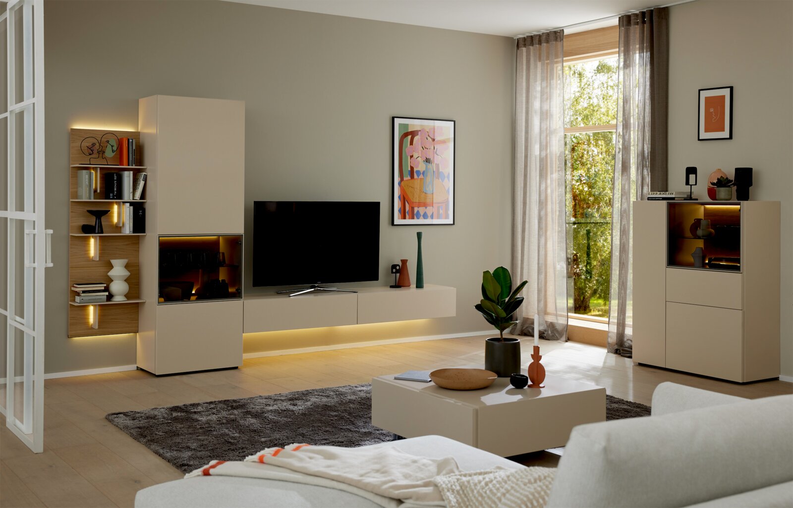 Modern modulair tv-meubel in beige en houtlook met vitrinekasten, wandplanken en sfeervolle ledverlichting, vanuit schuin vooraanzicht in een lichte woonkamer