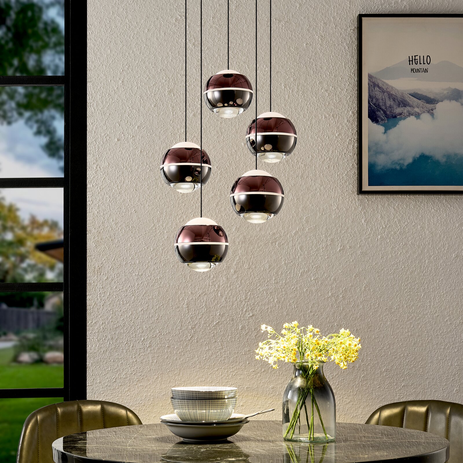 Moderne 5-flammige Pendelleuchte mit spiegelnden kugelförmigen Schirmen in Rauchglas-Optik über einem Esstisch, frontal in leicht erhöhter Perspektive aufgenommen.