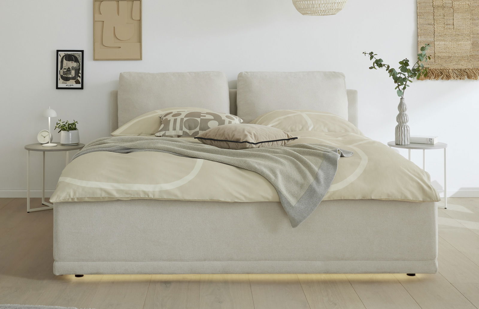 Frontale Ansicht eines modernen Polsterbettgestells in einem hellen Schlafzimmer mit neutralen Farben und stilvoller Dekoration.