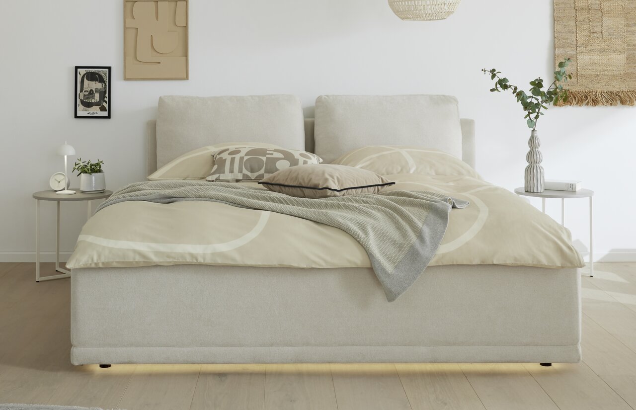 Frontale Ansicht eines modernen Polsterbettgestells in einem hellen Schlafzimmer mit neutralen Farben und stilvoller Dekoration.