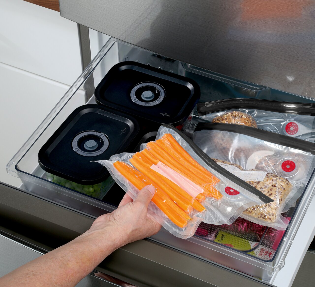 Vakuumier-Set EASYFRESH in einer Küchenschublade, mit vakuumierten Lebensmitteln wie Karotten und Brötchen, aus der Vogelperspektive betrachtet.