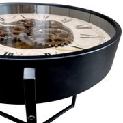 Ronde bijzettafel met een zwart metalen frame en een glazen blad, met daaronder een wijzerplaat met Romeinse cijfers en decoratieve tandwielen in steampunk-stijl, gezien vanuit een schuine close-up van bovenaf
