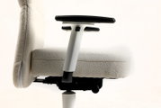 Seitenansicht eines ergonomischen Bürostuhls mit hellbeigem Stoffbezug, schwarzer gepolsterter Armlehne und weißem Armlehnenhalter vor hellem Hintergrund