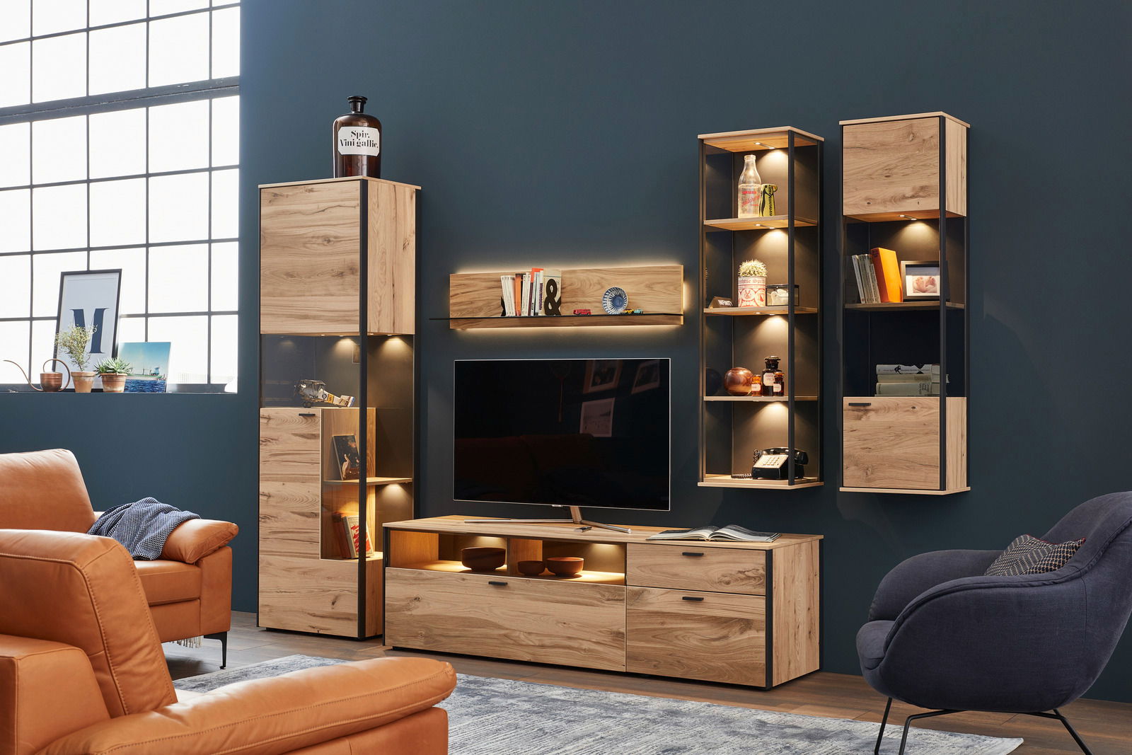 Schöner Wohnen Wandkombination ANDRA Moderne Wandkombination aus Holz mit integrierter Beleuchtung, bestehend aus mehreren Schränken und Regalen, frontal betrachtet.