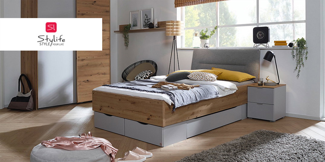 Schlafzimmer der Marke Stylife mit Holzbett und grauem Kopfteil