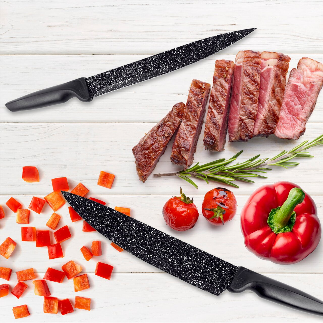 GOURMETMAXX Messerset 6-tlg. Zwei schwarze Messer mit gesprenkelter Klinge auf einem weißen Holztisch, umgeben von geschnittenem Steak, Paprikawürfeln, Tomaten und einem Rosmarinzweig. Draufsicht.