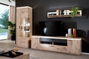 Woonkamerwand in eikenlook met tv-lowboard, vitrinekast met glazen deuren en wandplank, led-verlichting en zwarte accenten, gefotografeerd vanuit een vooraanzicht, lichtjes van links.