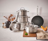 Topfset ELEGANCE 6-tlg. aus Edelstahl, bestehend aus mehreren Töpfen und einer Pfanne, auf einer Küchenarbeitsplatte arrangiert. Perspektive von vorne.
