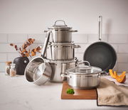 Topfset ELEGANCE 6-tlg. aus Edelstahl, bestehend aus mehreren Töpfen und einer Pfanne, auf einer Küchenarbeitsplatte arrangiert. Perspektive von vorne.