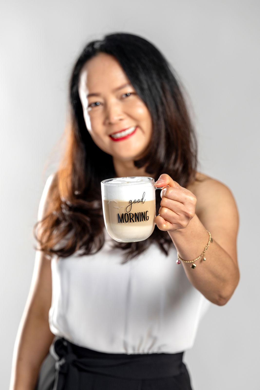 Frau hält eine Tasse mit der Aufschrift 'good MORNING' in der Hand, frontal fotografiert.