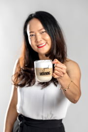 Frau hält eine Tasse mit der Aufschrift 'good MORNING' in der Hand, frontal fotografiert.