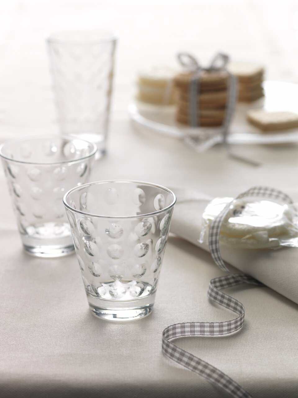 Trinkglas Optic 215ml mit gepunktetem Design, auf einem Tisch mit Serviette und Keksen, seitliche Perspektive