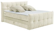 Beiges Boxspringbett mit gepolstertem Kopfteil und mehreren Kissen, seitliche Perspektive