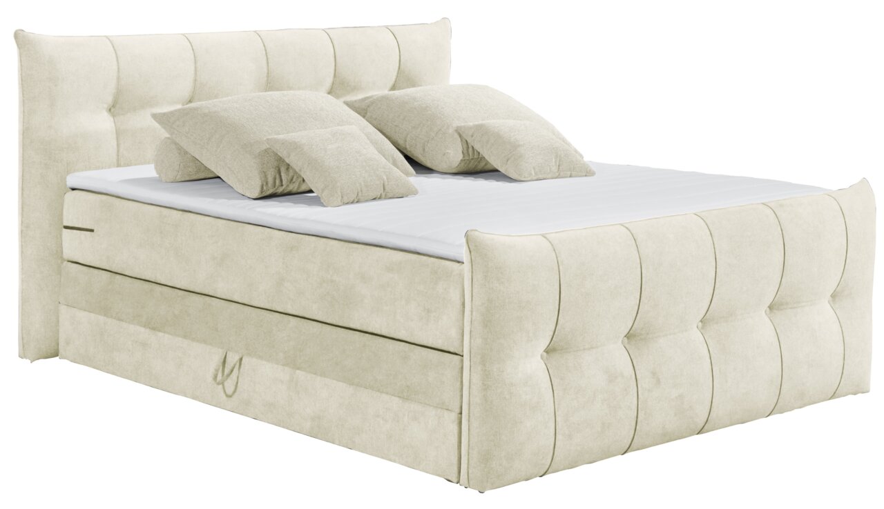 Beiges Boxspringbett mit gepolstertem Kopfteil und mehreren Kissen, seitliche Perspektive