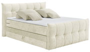 Beiges Boxspringbett mit gepolstertem Kopfteil und mehreren Kissen, seitliche Perspektive