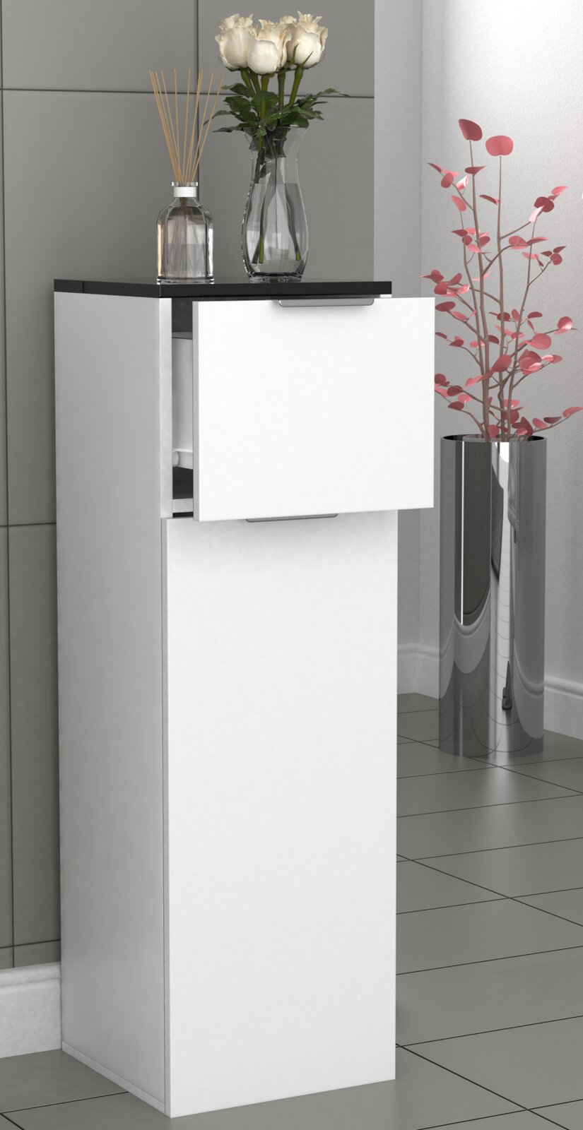Schmaler weißer Badschrank mit schwarzer Deckplatte und zwei Fronten, obere Klappe leicht geöffnet; darauf Glasvase mit weißen Rosen und Duftstäbchen, rechts daneben hoher silberner Pflanzkübel mit rosa Zweigen, aufgenommen in leichter Seitenansicht von v