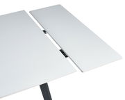 Nahaufnahme eines weißen, ausziehbaren Esstisches mit moderner, glatter Oberfläche und schwarzem Gestell.