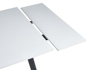 Nahaufnahme eines weißen, ausziehbaren Esstisches mit moderner, glatter Oberfläche und schwarzem Gestell.