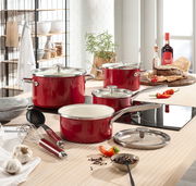 Rotes 6-teiliges Topfset aus Emaille auf einem modernen Küchentisch, fotografiert aus einer leicht erhöhten Perspektive.