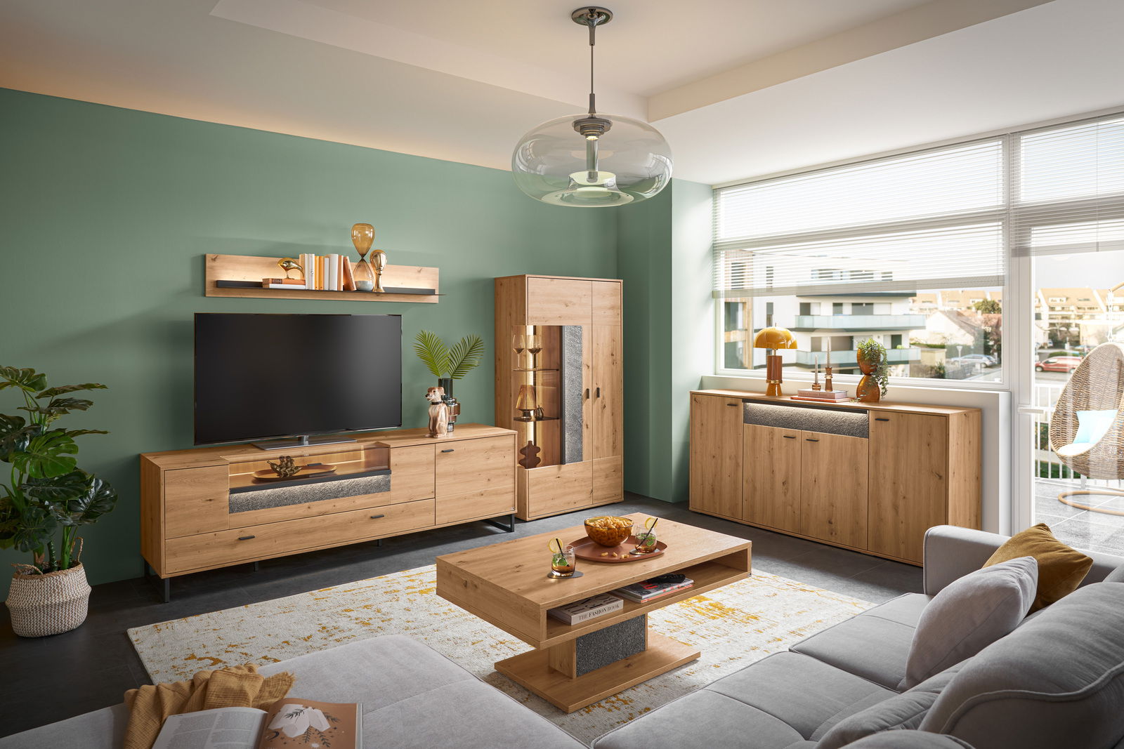 Moderner Couchtisch aus Holz mit rechteckiger Form, zentralem Stauraum und dekorativem Element, in einem stilvollen Wohnzimmer mit grüner Wand und großen Fenstern, aus der Perspektive von einem Sofa aus gesehen.