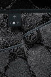 Nahaufnahme eines grauen Saunatuchs mit schwarzem Etikett der Marke JOOP! und floralen Mustern.