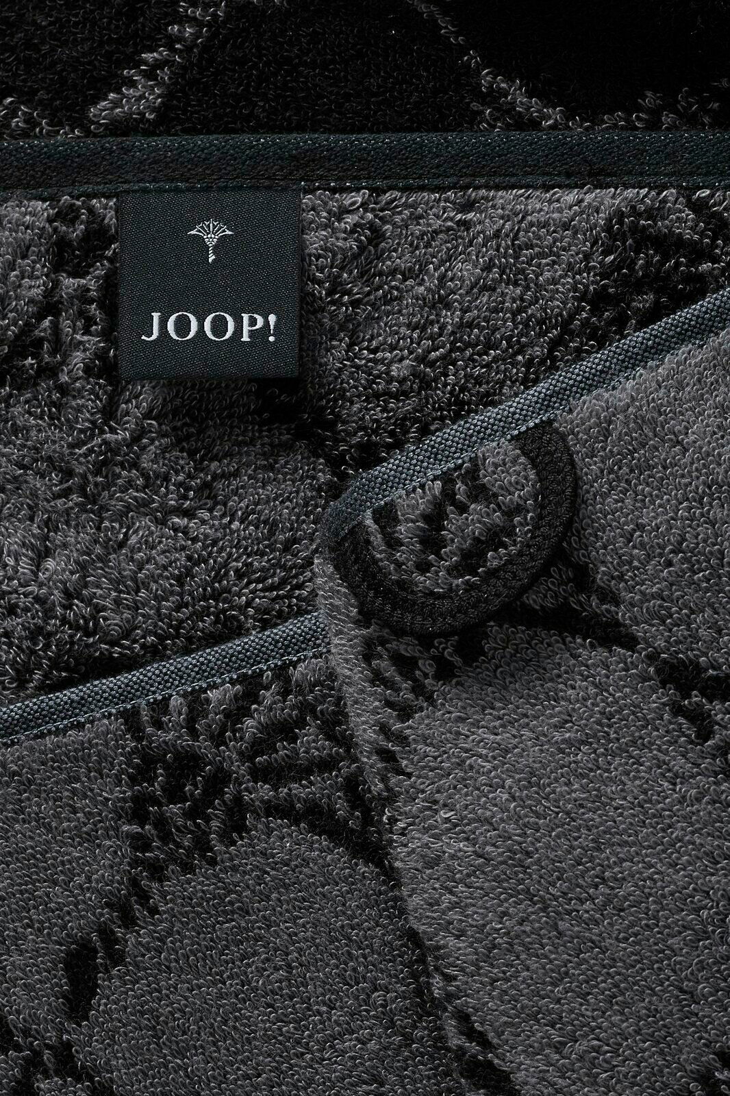 Nahaufnahme eines grauen Saunatuchs mit schwarzem Etikett der Marke JOOP! und floralen Mustern.