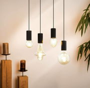 Vier hängende Pendelleuchten mit unterschiedlichen, kunstvoll gestalteten Glühbirnen in einem modernen Raum, seitliche Perspektive.