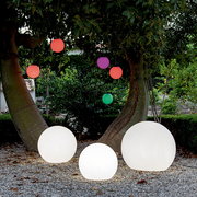 Drei leuchtende Kugelleuchten BULY 30 im Freien, umgeben von Bäumen und bunten hängenden Kugeln, aus der Perspektive von vorne.