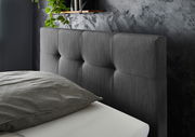 Nahaufnahme eines grauen Boxspringbett-Kopfteil mit gepolstertem Design, seitliche Perspektive
