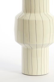 Nahaufnahme aus frontaler Perspektive einer cremefarbenen Keramikvase mit glänzender Oberfläche, markanter Silhouette und feinen, unregelmäßigen Längslinien.