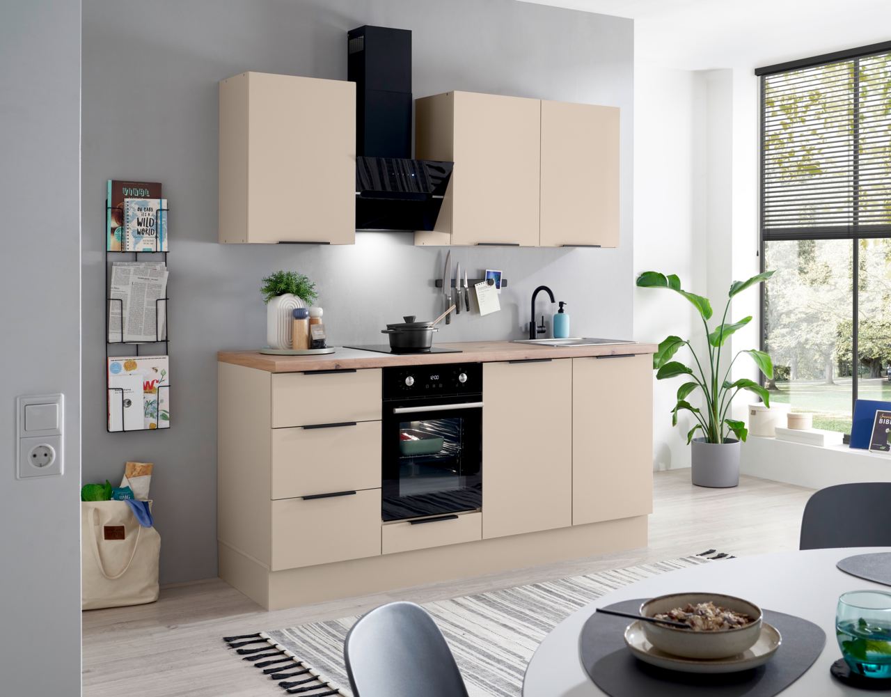 Moderne Küchenzeile in Beige mit Holzarbeitsplatte, schwarzen Griffen, integriertem Backofen, Kochfeld, Spüle und schwarzer Dunstabzugshaube, frontal aus leicht schräger Perspektive fotografiert