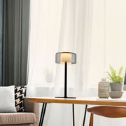 Moderne Tischleuchte RIKA auf einem Tisch in einem gemütlichen Wohnzimmer, seitliche Perspektive.