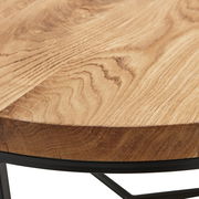 Nahaufnahme eines runden Couchtisches mit einer Holzplatte und einem schwarzen Metallgestell, seitliche Perspektive