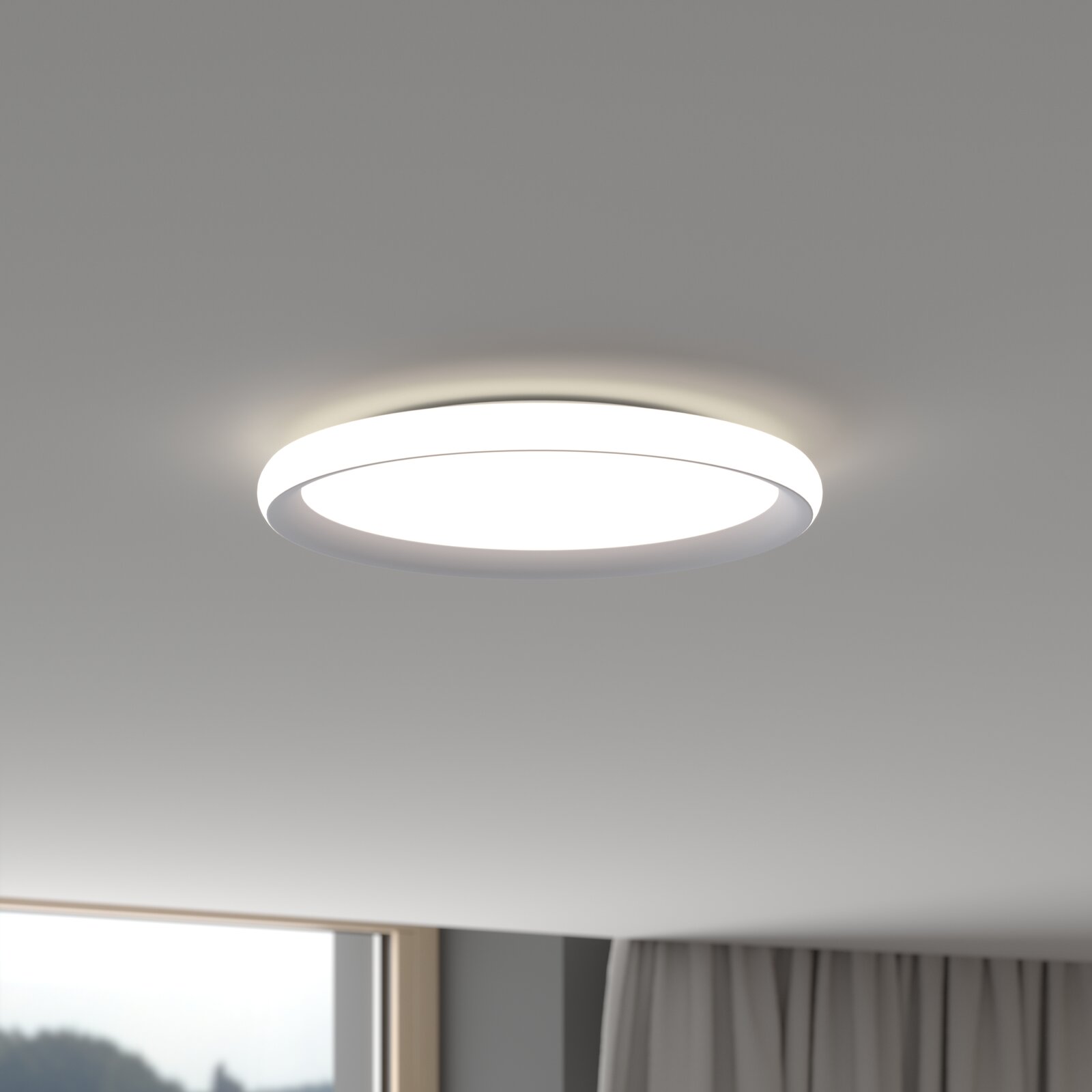 Runde, flache LED-Deckenleuchte in Weiß an der Zimmerdecke, eingeschaltet und mit gleichmäßigem warmweißem Licht; Ansicht leicht von unten in einem Wohnraum.