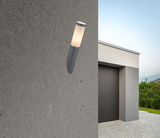 Moderne Außenleuchte BOSTON an einer Betonwand, seitliche Perspektive, mit einem Haus im Hintergrund.